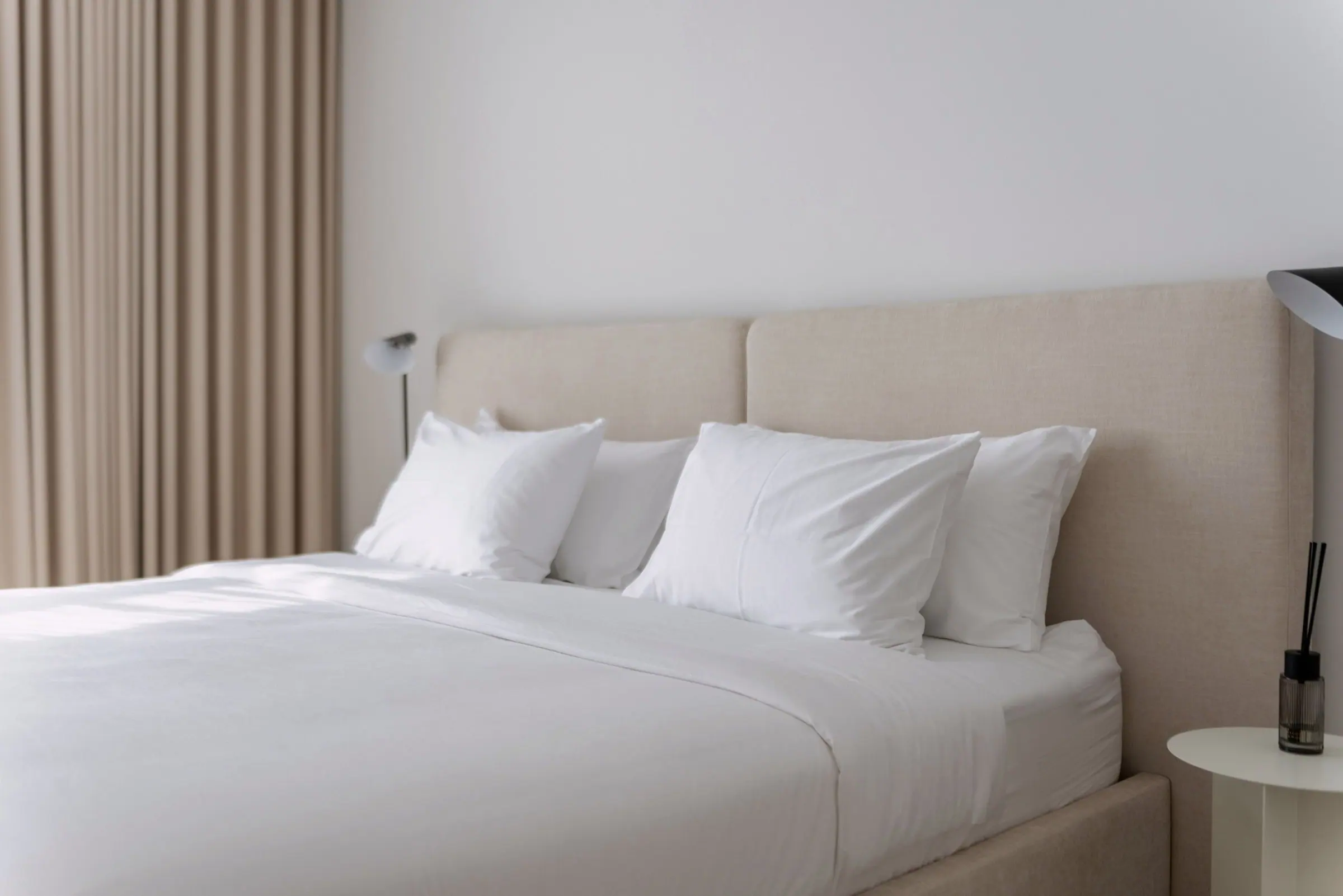 Lichte slaapkamer met een opgemaakt bed met wit beddengoed