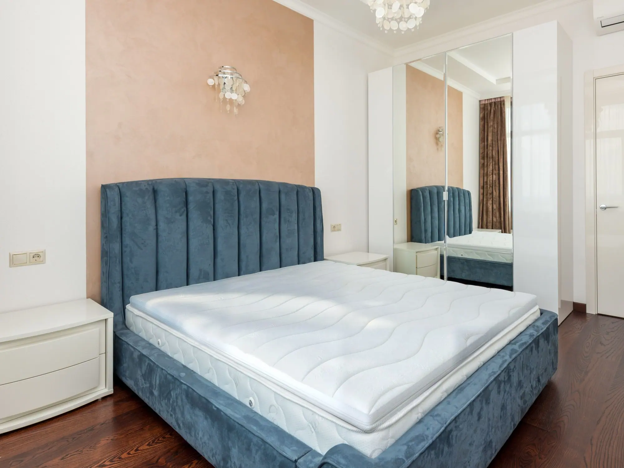 Topper van Toros Bedden op een matras in een bed met blauw fluwelen hoofdbord